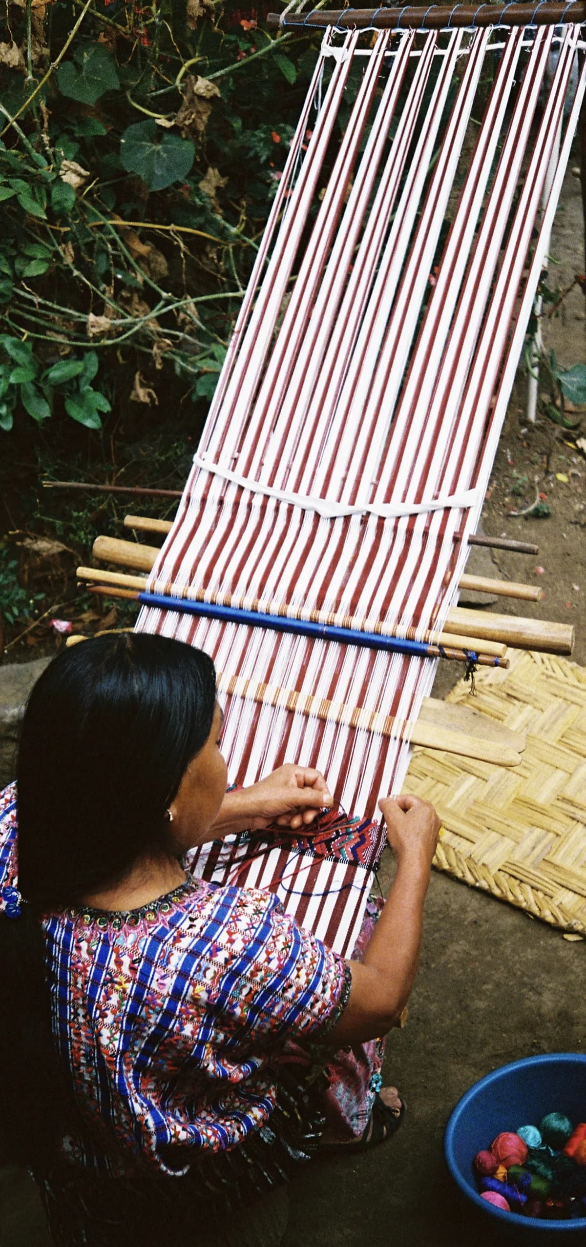 Mayan woman weaving traditional textile on backstrap loom by Lake Atitlán